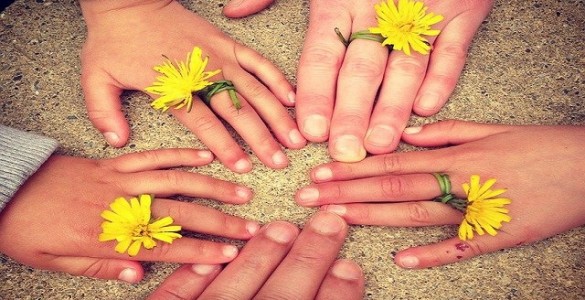 fünf zusammengehaltene Hände mit Blumen